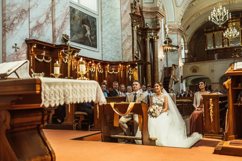 A pár az oltárnál, a háttérben a templomi vendégek