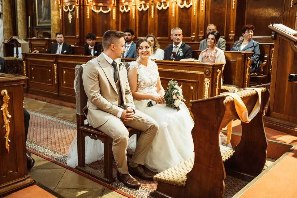 Enikő és Marcell ülve figyelnek a templomi szertartáson