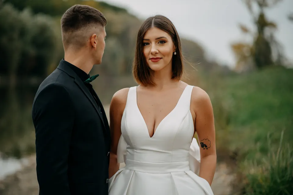 Rebeka és Martin: A menyasszony a kamerába néz, a vőlegény felé fordul.