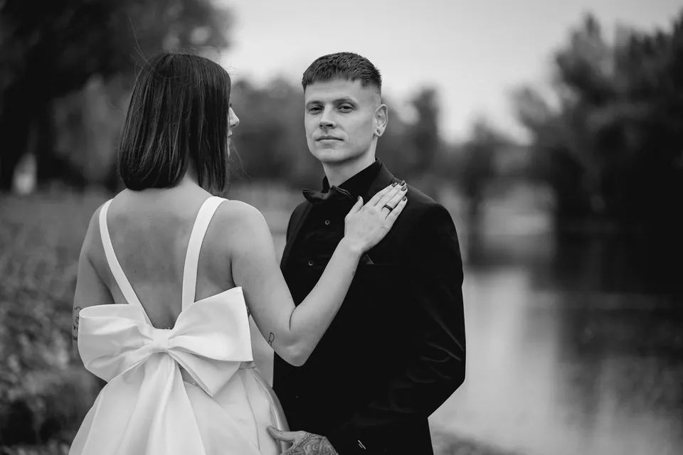 Rebeka és Martin: Fekete-fehér páros portré, a menyasszony ruhájának hátán masnival.