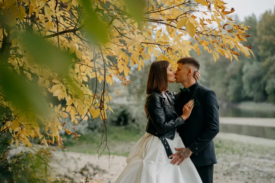 Rebeka és Martin: Csók a sárguló levelek alatt, a menyasszony fekete kabátban.