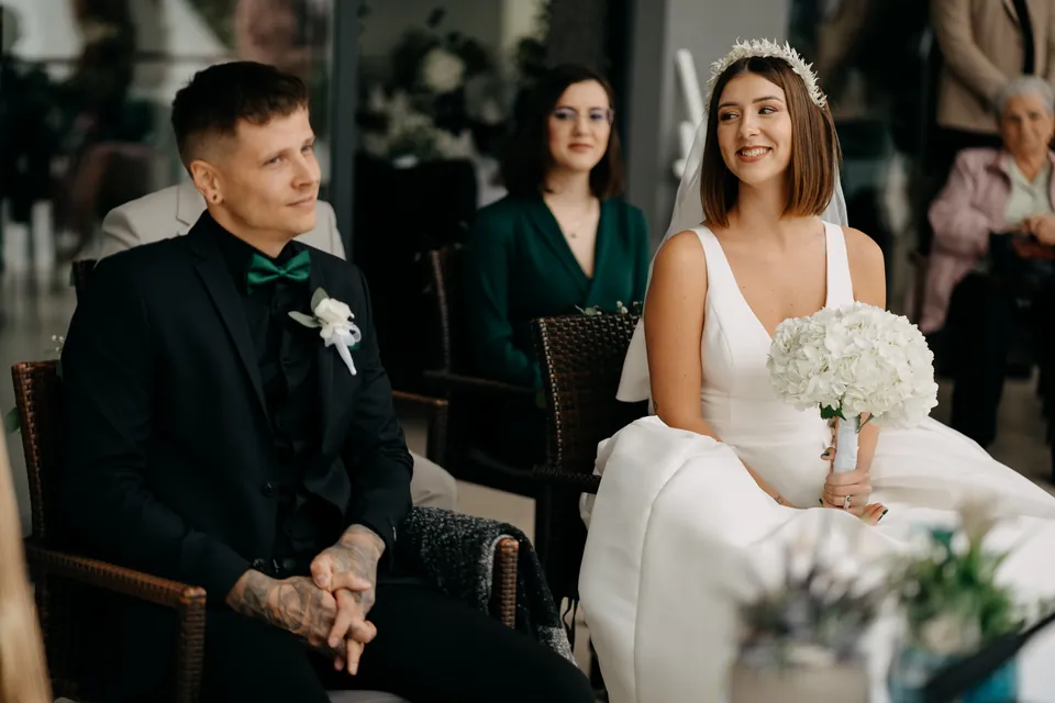 Rebeka és Martin: A vőlegény a mosolygó menyasszonyra néz a szertartáson.