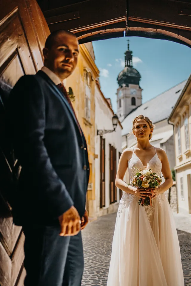 Tünde és Albert városi kapualjban, a háttérben templomtorony